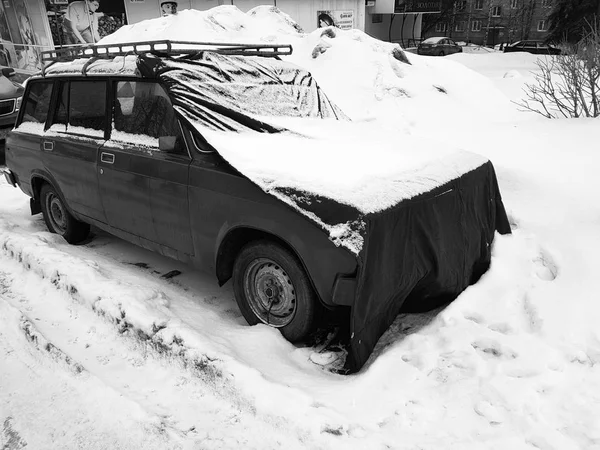 Beautiful old car with a cover on the hood in the snow — Stock Photo, Image