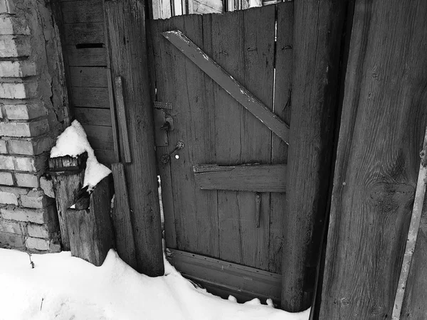 Старые ворота с забором у входа в кирпичный дом на фоне снега зимой — стоковое фото