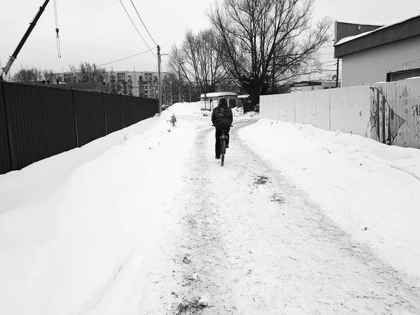 Un hombre monta una bicicleta a través de la nieve en invierno . — Foto de Stock