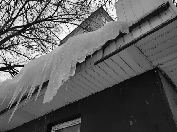 Опасные сосульки и лед на крыше весной или зимой — стоковое фото