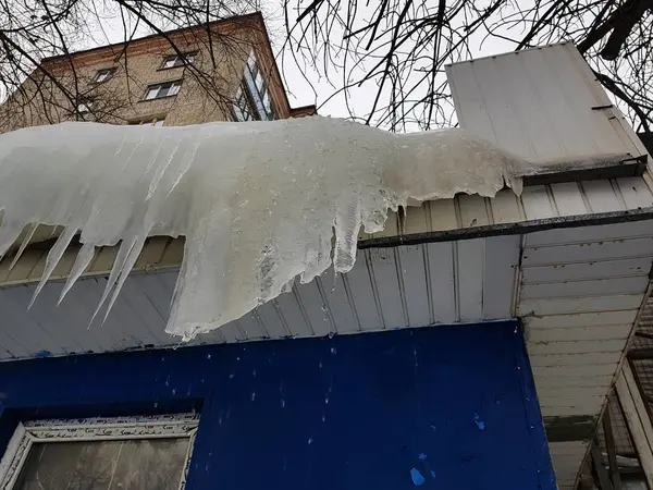 Niebezpieczne sople i lód na dachu wiosną lub zimą — Zdjęcie stockowe