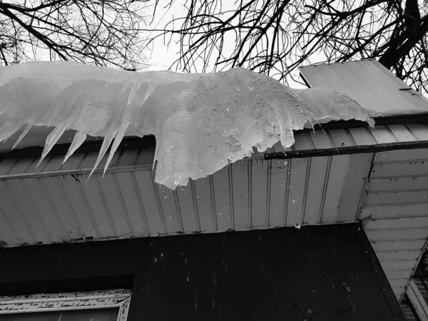Carámbanos peligrosos y hielo en el techo en primavera o invierno — Foto de Stock