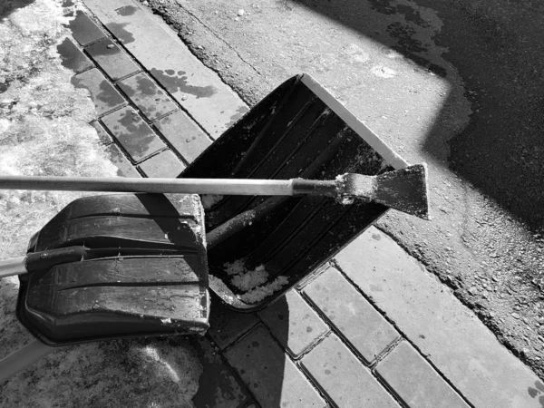 Pá de neve e machado de gelo na neve contra o fundo de uma telha e cerca na primavera ou inverno — Fotografia de Stock