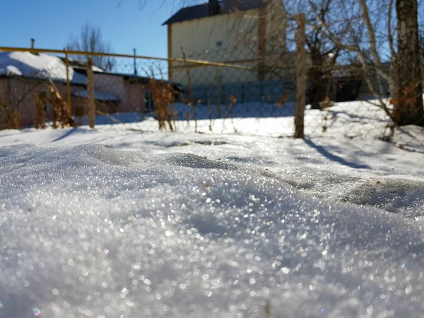Snow csillog a napsugarak a háttérben a csővezeték és a házak a télen vagy tavasszal — Stock Fotó