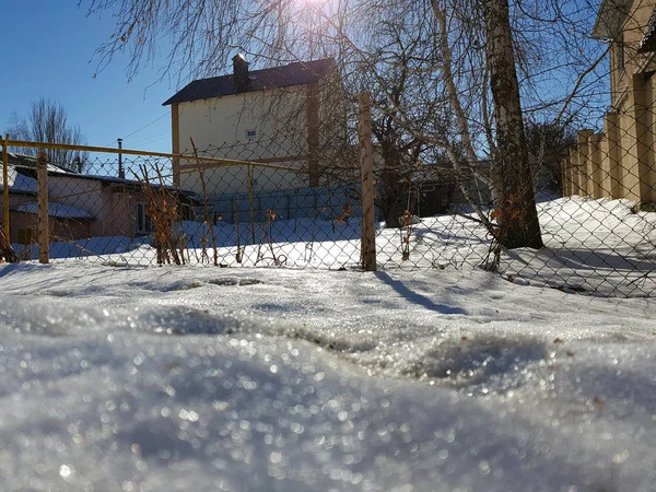 Nieve brilla en los rayos del sol en el fondo de la tubería y casas en el invierno o la primavera — Foto de Stock