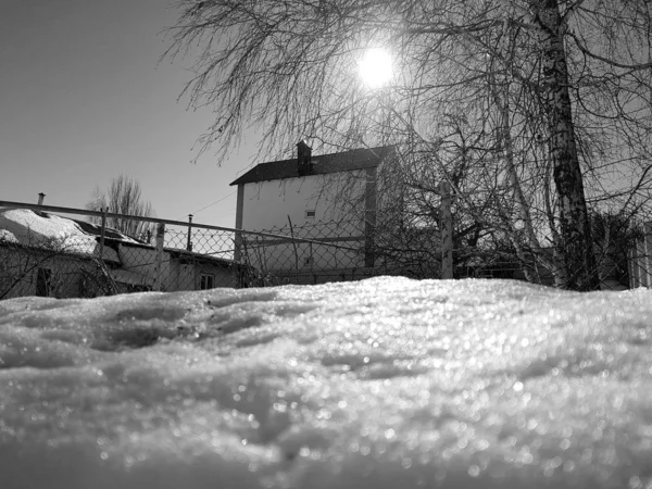 Neve brilha nos raios do sol no fundo do oleoduto e casas no inverno ou na primavera — Fotografia de Stock