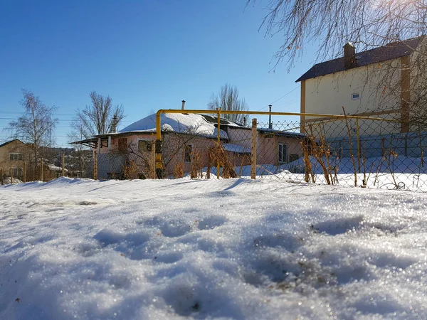 Сніг блищить в променях сонця на фоні трубопроводу і будинків взимку або навесні — стокове фото