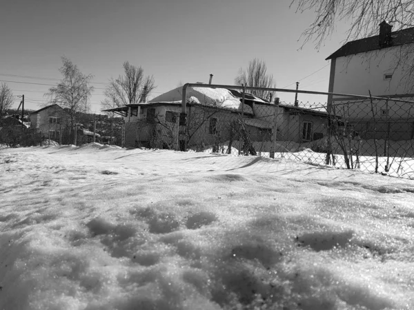 Сніг блищить в променях сонця на фоні трубопроводу і будинків взимку або навесні — стокове фото