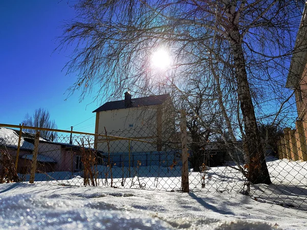 Snow glitters in the rays of the sun on the background of the pipeline and houses in the winter or spring — Stock Photo, Image