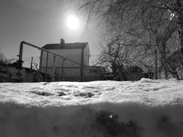 Snö glittrar i solens strålar på bakgrunden av rörledningen och hus på vintern eller våren — Stockfoto