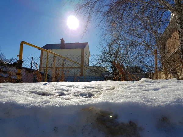 Nieve brilla en los rayos del sol en el fondo de la tubería y casas en el invierno o la primavera — Foto de Stock