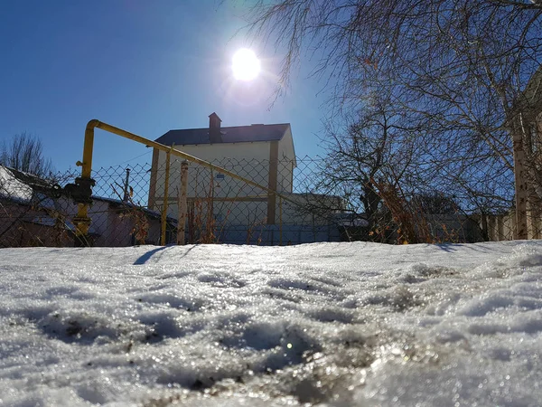 Nieve brilla en los rayos del sol en el fondo de la tubería y casas en el invierno o la primavera — Foto de Stock