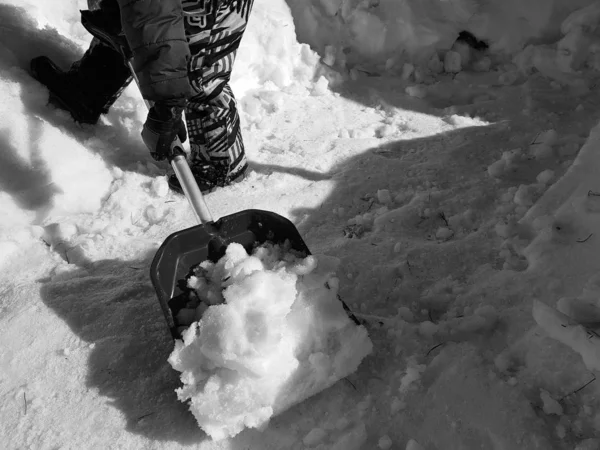 Φτυάρι χιονιού στα χέρια-το παιδί καθαρίζει το χιόνι το χειμώνα ή την άνοιξη — Φωτογραφία Αρχείου