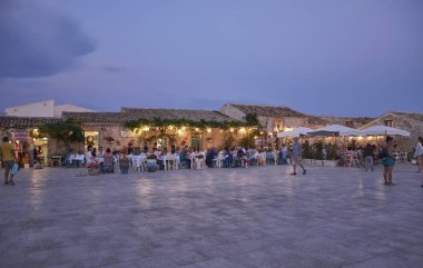 İtalya, Sicilya, Marzamemi (Siracusa eyaleti); 10 Temmuz 2018, insanlar ve gün batımında - editoryal küçük şehrin eski kısmı restoranlarda