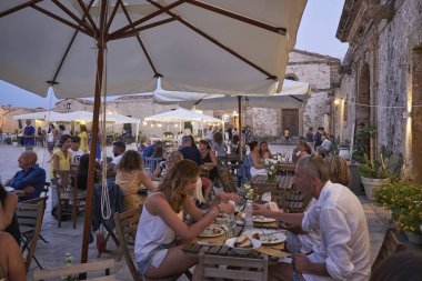 İtalya, Sicilya, Marzamemi (Siracusa eyaleti); 10 Temmuz 2018, insanlar ve gün batımında - editoryal küçük şehrin eski kısmı restoranlarda