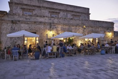 İtalya, Sicilya, Marzamemi (Siracusa eyaleti); 10 Temmuz 2018, insanlar ve gün batımında - editoryal küçük şehrin eski kısmı restoranlarda