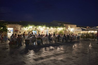 İtalya, Sicilya, Marzamemi (Siracusa eyaleti); 10 Temmuz 2018, insanlar ve gün batımında - editoryal küçük şehrin eski kısmı restoranlarda