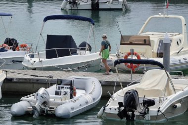 İtalya, Sicilya, Akdeniz, Marina di Ragusa; 5 Ağustos 2018, Genç bir çocuk ve motorlu tekneler limanda - Editörden