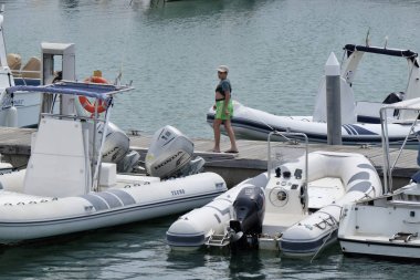İtalya, Sicilya, Akdeniz, Marina di Ragusa; 5 Ağustos 2018, Genç bir çocuk ve motorlu tekneler limanda - Editörden