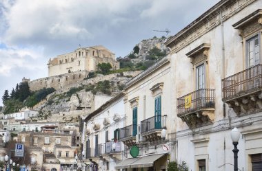 İtalya, Sicilya, Scicli (Ragusa eyaletinde); 28 Mart 2019, Italia Meydanı'nda Barok binalar ve Santa Maria della Croce Manastırı (sn XVI) kadar tepede - Editörden