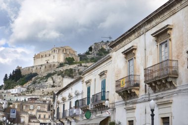 İtalya, Sicilya, Scicli (Ragusa eyaletinde); 28 Mart 2019, Italia Meydanı'nda Barok binalar ve Santa Maria della Croce Manastırı (sn XVI) kadar tepede - Editörden
