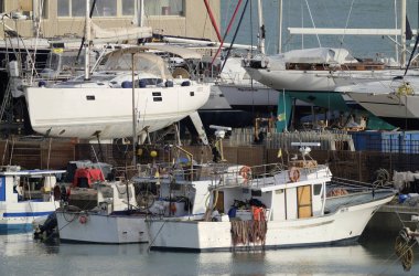 İtalya, Sicilya, Akdeniz, Marina di Ragusa; 5 Nisan 2019, ahşap balıkçı tekneleri ve limanda Lüks Yatlar-editoryal