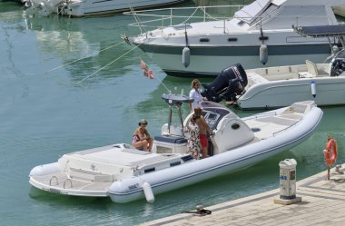 İtalya, Sicilya, Akdeniz, Marina di Ragusa (Ragusa Eyaleti); 16 Haziran 2019, limanda büyük bir lastik teknede insanlar - Editörden