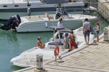 İtalya, Sicilya, Akdeniz, Marina di Ragusa (Ragusa Eyaleti); 16 Haziran 2019, limanda büyük bir lastik teknede insanlar - Editörden