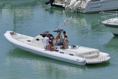 İtalya, Sicilya, Akdeniz, Marina di Ragusa (Ragusa Eyaleti); 16 Haziran 2019, limanda büyük bir lastik teknede insanlar - Editörden