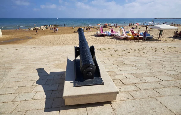 İtalya, Sicilya, Akdeniz, Marina di Ragusa (Ragusa Eyaleti), sahilde eski bir top ve sahilde insanlar