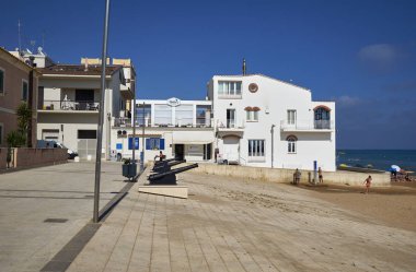 İtalya, Sicilya, Akdeniz, Marina di Ragusa (Ragusa Eyaleti); 19 Haziran 2019, sahilde eski toplar ve sahilde insanlar - Editörden