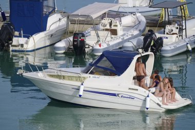 İtalya, Sicilya, Akdeniz, Marina di Ragusa (Ragusa Eyaleti); 23 Haziran 2019, limanda bir motorlu teknede insanlar - Editörden