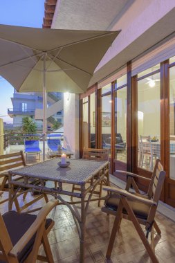 İtalya, Sicilya, Marina di Ragusa (Ragusa Eyaleti); 3 Temmuz 2019, zarif özel daire, gün batımında yemek masası ile teras görünümü - Editörden