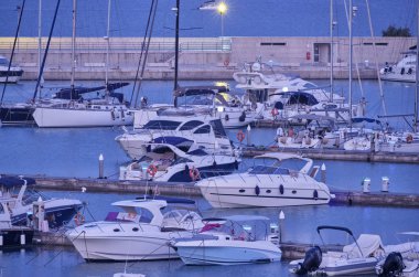 İtalya, Sicilya, Akdeniz, Marina di Ragusa (Ragusa Eyaleti); 19 Temmuz 2019, gün batımında limanda motorlu tekneler ve lüks yatlar - Editörden Haberler