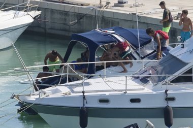 İtalya, Sicilya, Akdeniz, Marina di Ragusa (Ragusa eyaleti); 25 Temmuz 2019, bir motorlu tekne ve limanda Lüks Yatlar insanlar-editoryal
