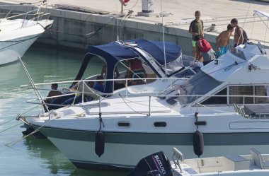 İtalya, Sicilya, Akdeniz, Marina di Ragusa (Ragusa eyaleti); 25 Temmuz 2019, bir motorlu tekne ve limanda Lüks Yatlar insanlar-editoryal