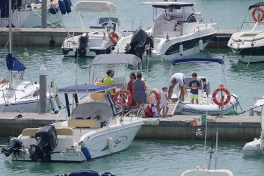 İtalya, Sicilya, Akdeniz, Marina di Ragusa (Ragusa Eyaleti); 3 Ağustos 2019' da limanda insanlar, motorlu tekneler ve lüks yatlar - Editörden