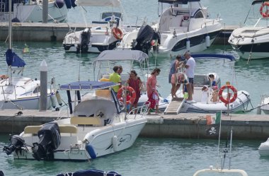 İtalya, Sicilya, Akdeniz, Marina di Ragusa (Ragusa Eyaleti); 3 Ağustos 2019' da limanda insanlar, motorlu tekneler ve lüks yatlar - Editörden