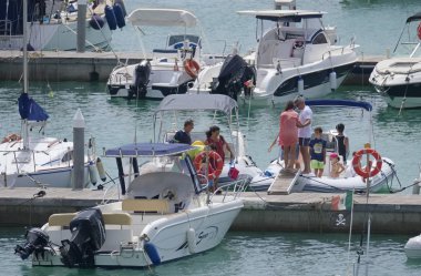 İtalya, Sicilya, Akdeniz, Marina di Ragusa (Ragusa Eyaleti); 3 Ağustos 2019' da limanda insanlar, motorlu tekneler ve lüks yatlar - Editörden