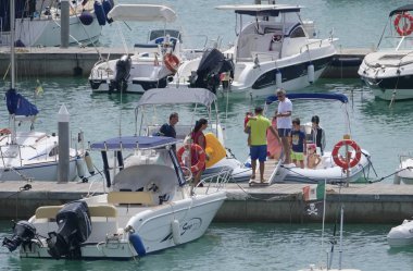 İtalya, Sicilya, Akdeniz, Marina di Ragusa (Ragusa Eyaleti); 3 Ağustos 2019' da limanda insanlar, motorlu tekneler ve lüks yatlar - Editörden