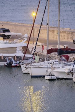 İtalya, Sicilya, Akdeniz, Marina di Ragusa (Ragusa Eyaleti); 8 Ağustos 2019, gün batımında limanda motorlu tekneler ve lüks yatlar - Editörden