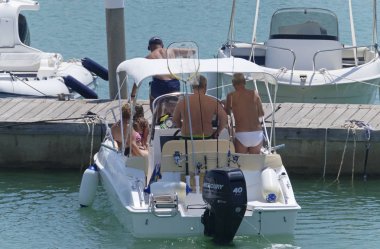 İtalya, Sicilya, Akdeniz, Marina di Ragusa (Ragusa Eyaleti); 10 Ağustos 2019, limanda bir motorlu teknede insanlar - Editörden