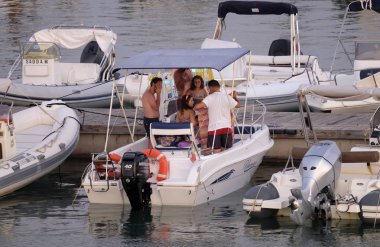 İtalya, Sicilya, Akdeniz, Marina di Ragusa (Ragusa Eyaleti); 11 Ağustos 2019, gün batımında limanda motorlu teknede insanlar - Editörden