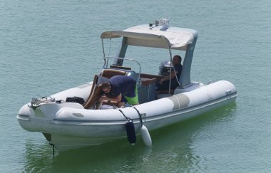 İtalya, Sicilya, Akdeniz, Marina di Ragusa (Ragusa Eyaleti); 27 Ağustos 2019, limanda lastik botta insanlar - Editörden