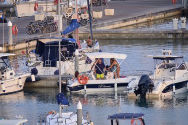 İtalya, Sicilya, Akdeniz, Marina di Ragusa (Ragusa Eyaleti); 29 Ağustos 2019, limanda bir motorlu teknede insanlar - Editörden