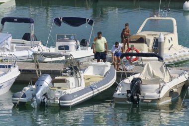 İtalya, Sicilya, Akdeniz, Marina di Ragusa (Ragusa Eyaleti); 31 Ağustos 2019, limanda insanlar ve motorlu tekneler - Editörden