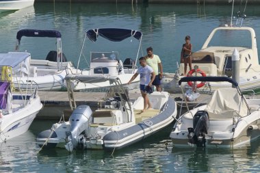 İtalya, Sicilya, Akdeniz, Marina di Ragusa (Ragusa Eyaleti); 31 Ağustos 2019, limanda insanlar ve motorlu tekneler - Editörden