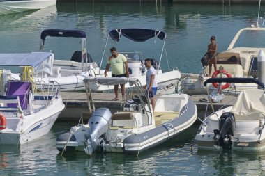 İtalya, Sicilya, Akdeniz, Marina di Ragusa (Ragusa Eyaleti); 31 Ağustos 2019, limanda insanlar ve motorlu tekneler - Editörden