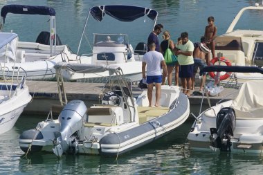 İtalya, Sicilya, Akdeniz, Marina di Ragusa (Ragusa Eyaleti); 31 Ağustos 2019, limanda insanlar ve motorlu tekneler - Editörden