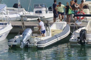 İtalya, Sicilya, Akdeniz, Marina di Ragusa (Ragusa Eyaleti); 31 Ağustos 2019, limanda insanlar ve motorlu tekneler - Editörden